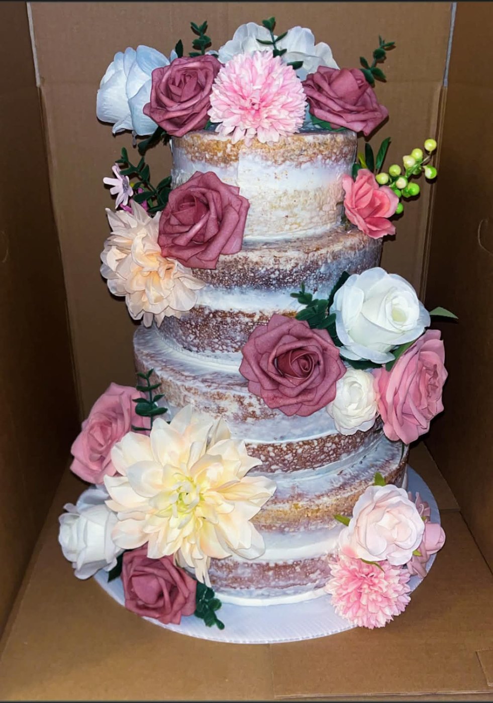 Four-tier naked wedding cake trimmed with blush and ivory flowers